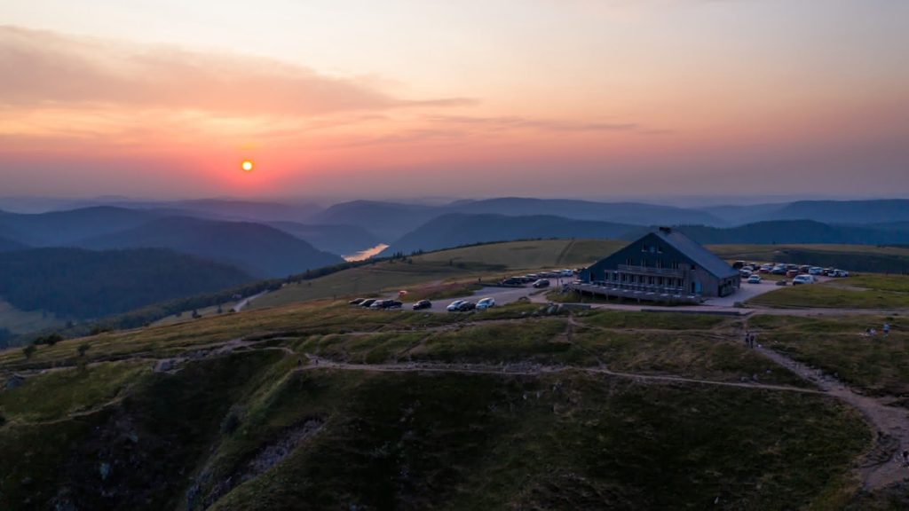 Vue panoramique du chalet Le Pourquoi Pas à La Bresse au coucher du soleil, avec vue sur les montagnes environnantes.