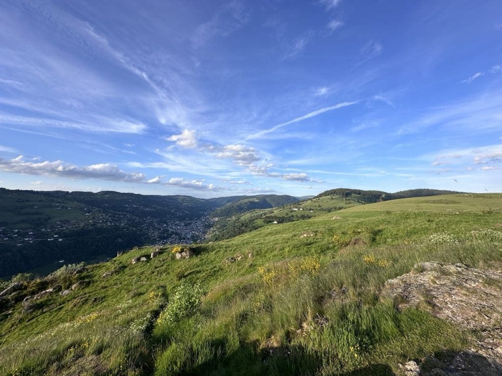 Paysage de montagnes verdoyantes sous un ciel bleu avec des nuages, vue panoramique en Alsace.